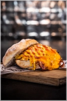 Huisgebraden beenham, langzaam gegaard met verse rozemarijn,knoflook, tijm, peper en zout. Daarbij gaat gesmolten cheddar, ijsbergsla en onze huisgemaakte honingmosterdsaus <br><i>Dit samen zorgt voor een heerlijke smaaksensatie</i>.