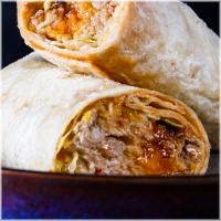 200 gram malse geplukte kippendijen gemarineerd in onze huisgemaakte chillisaus met verse chedder en warm uit de oven geserveerd. <br><br><i>BiggBoss pulled chili chicken wrap</i>!