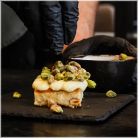 Onze heerlijke fluffy blondie brownie met een topping van witte chocoladesaus en gebrande pistachenoten. <br><br><i>Every bite needs to be perfect!</i>